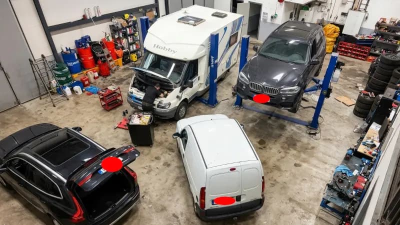 Mekaniker reparerar motor på husbil med öppen motorhuv i bilverkstad i Järfälla