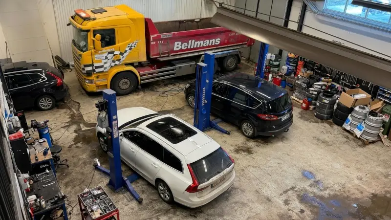 Verkstadshall med lastbil och personbilar på billyft hos Expert Verkstad i Järfälla